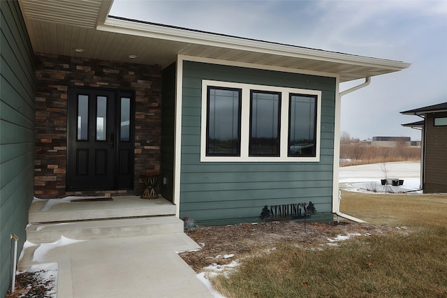 view of exterior entry featuring a lawn