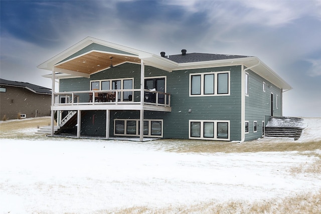 snow covered back of property featuring a wooden deck