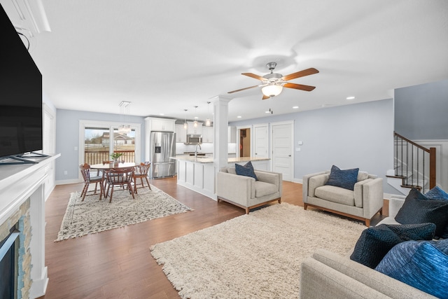 living room with a fireplace, decorative columns, sink, hardwood / wood-style flooring, and ceiling fan