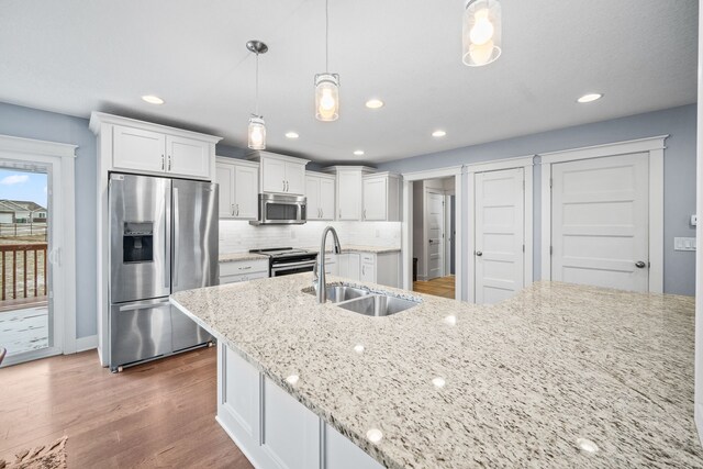 kitchen featuring pendant lighting, sink, white cabinetry, stainless steel appliances, and light stone counters