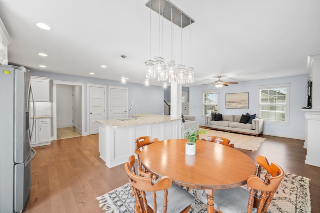 dining room featuring sink, ceiling fan, and light wood-type flooring