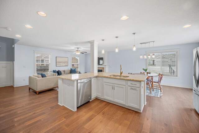 kitchen featuring sink, a kitchen island with sink, stainless steel appliances, white cabinets, and decorative light fixtures