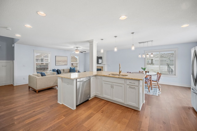 kitchen featuring white cabinetry, a center island with sink, hanging light fixtures, sink, and appliances with stainless steel finishes