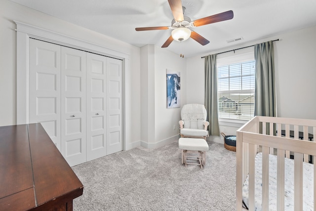 bedroom featuring ceiling fan, a closet, a nursery area, and carpet flooring