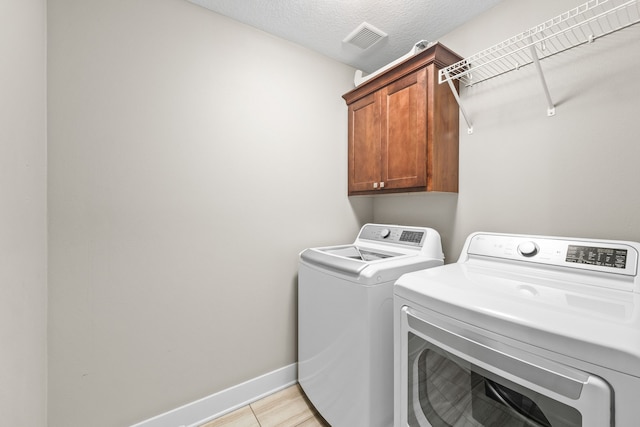 washroom featuring washer and dryer, cabinets, and a textured ceiling