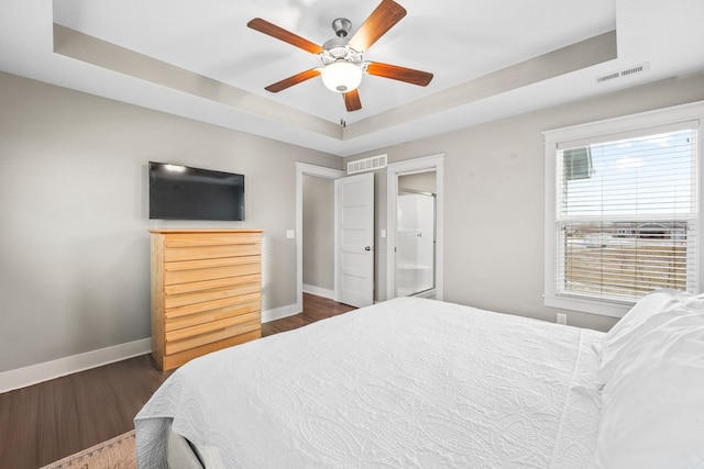 bedroom featuring dark hardwood / wood-style floors, a raised ceiling, and ceiling fan