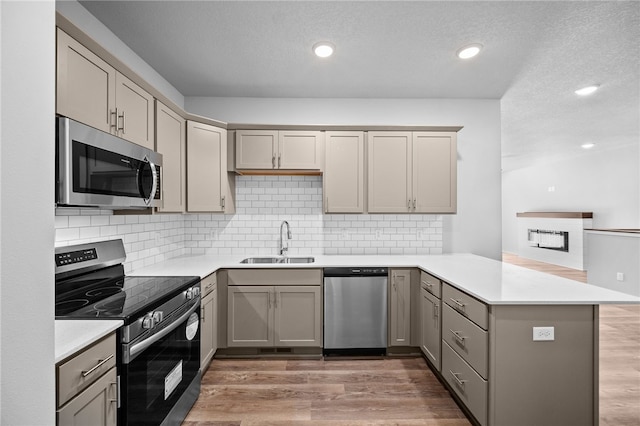 kitchen with stainless steel appliances, tasteful backsplash, sink, and kitchen peninsula