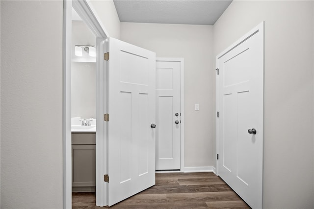 corridor featuring dark hardwood / wood-style flooring, sink, and a textured ceiling