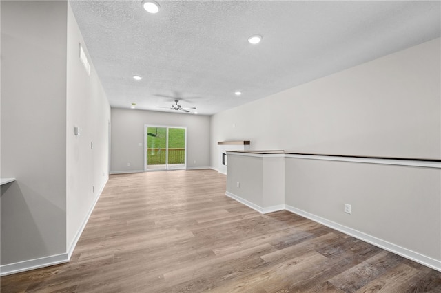 unfurnished room featuring a textured ceiling, light hardwood / wood-style flooring, and ceiling fan