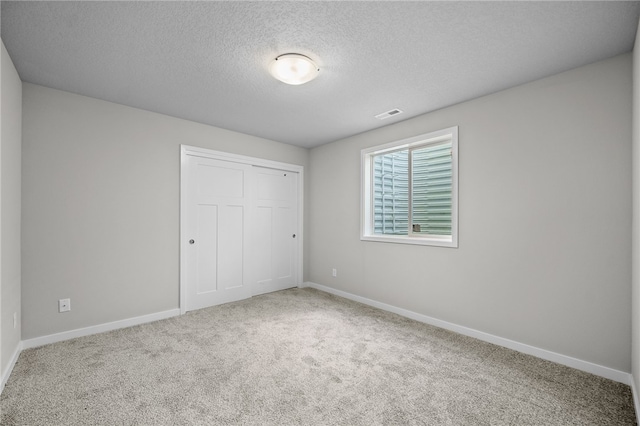 unfurnished bedroom with a closet, a textured ceiling, and carpet flooring