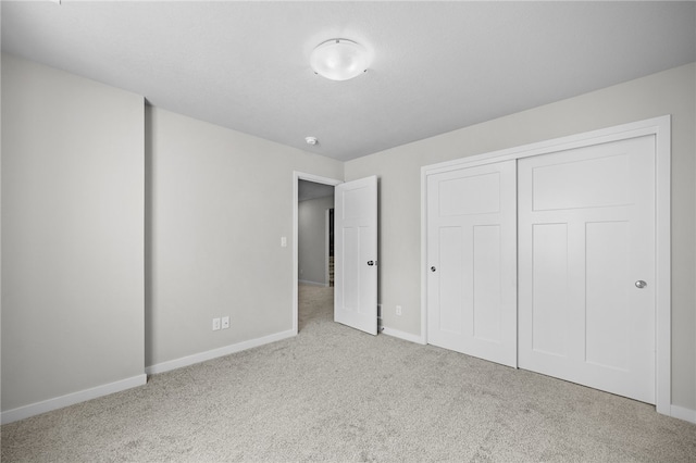 unfurnished bedroom with light colored carpet and a closet