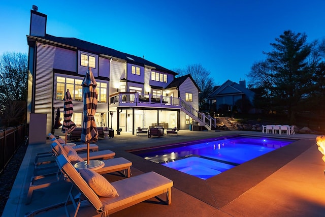 pool at dusk with a patio area and an in ground hot tub