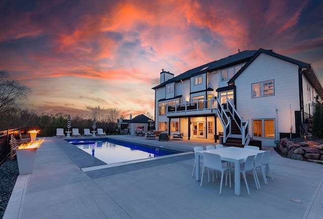 pool at dusk with an outdoor fire pit and a patio area