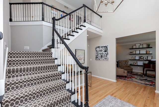 stairs featuring hardwood / wood-style floors, crown molding, and a towering ceiling