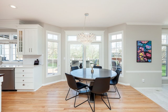 dining area with crown molding, a notable chandelier, and light wood-type flooring