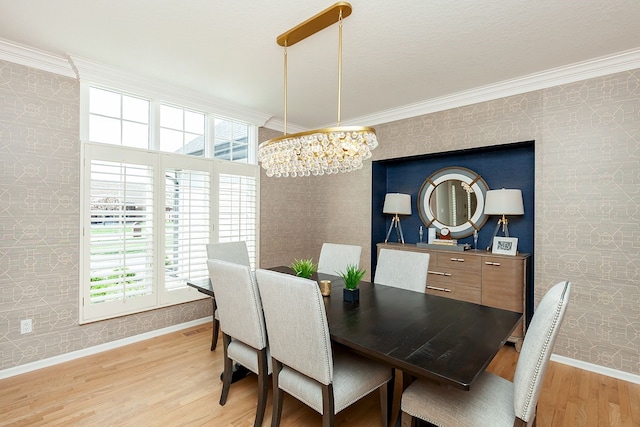 dining area with a notable chandelier, ornamental molding, and light wood-type flooring