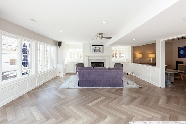 living room with ceiling fan, light parquet flooring, and a high end fireplace