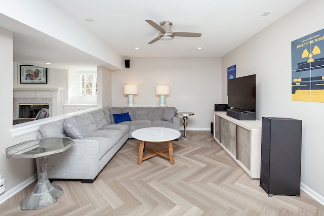 living room featuring ceiling fan, a premium fireplace, and light parquet flooring