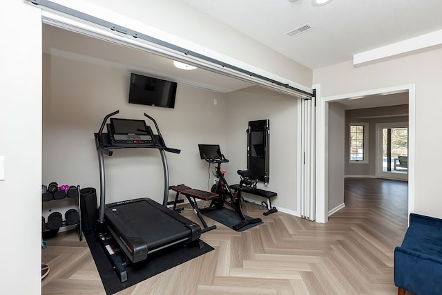 exercise room with a barn door and light parquet floors