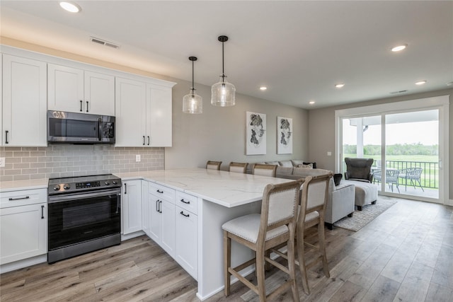 kitchen featuring white cabinetry, a breakfast bar area, hanging light fixtures, kitchen peninsula, and stainless steel appliances