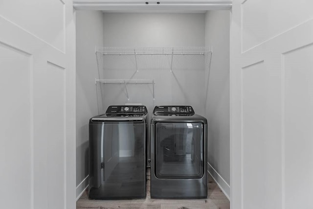 washroom with washing machine and clothes dryer and hardwood / wood-style floors