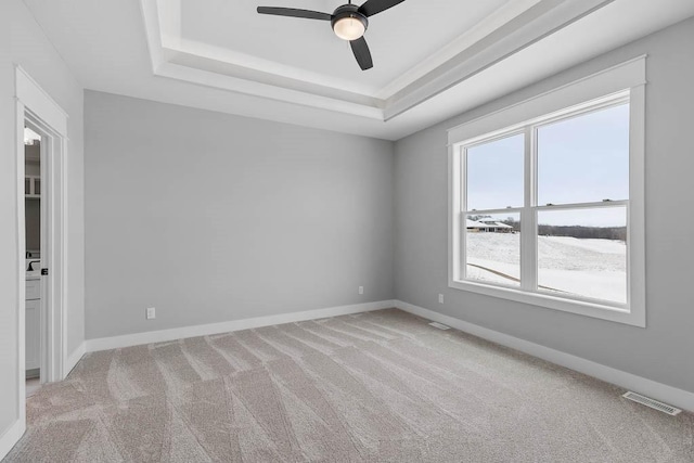 carpeted empty room featuring a tray ceiling and ceiling fan