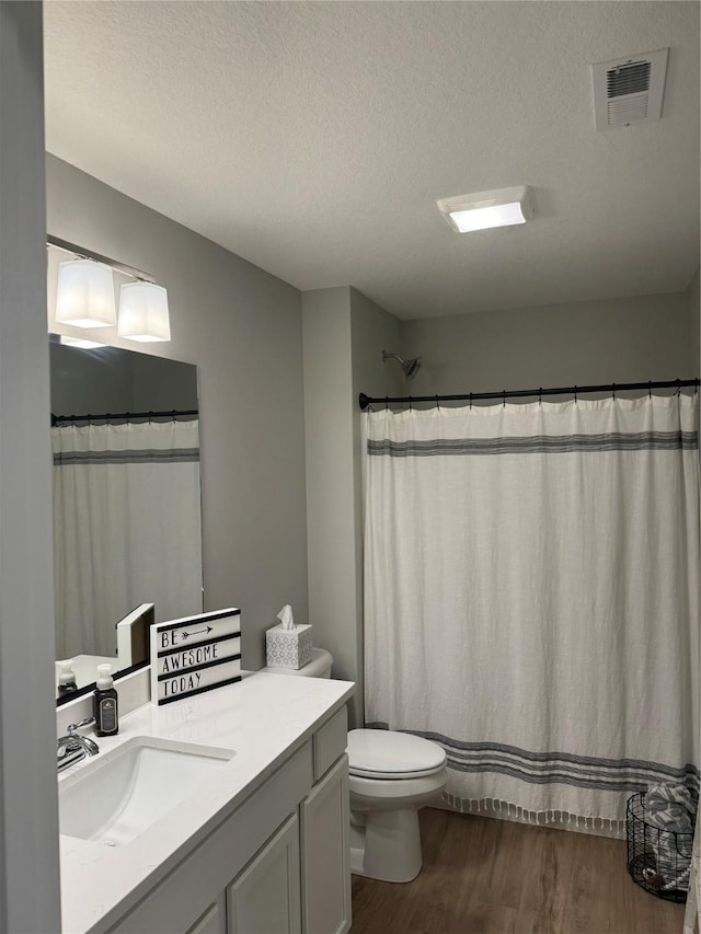 bathroom with vanity, wood-type flooring, a textured ceiling, toilet, and walk in shower