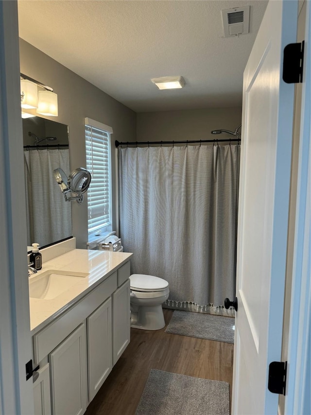 bathroom featuring hardwood / wood-style flooring, vanity, toilet, and a textured ceiling