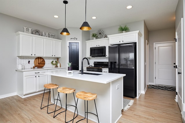 kitchen with black fridge, sink, and white cabinets