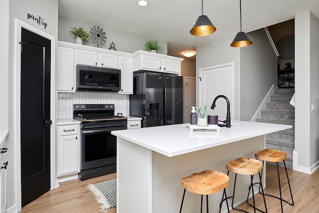 kitchen with electric stove, a kitchen island with sink, black refrigerator with ice dispenser, and white cabinets