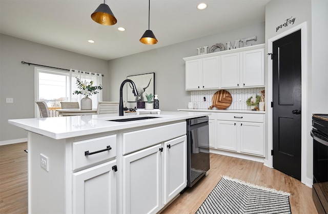 kitchen with pendant lighting, white cabinetry, sink, a kitchen island with sink, and black appliances