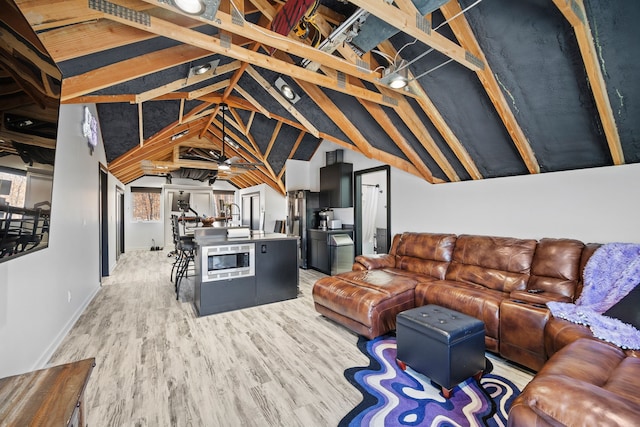 living room with light hardwood / wood-style floors and vaulted ceiling with beams