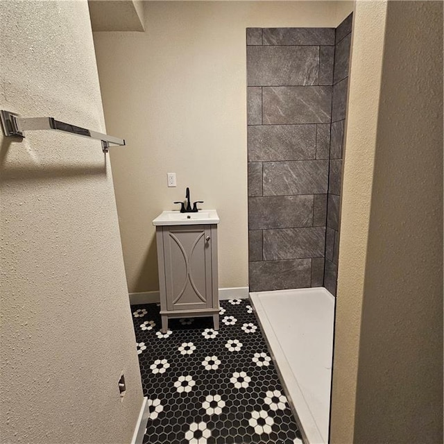 bathroom featuring tiled shower and vanity