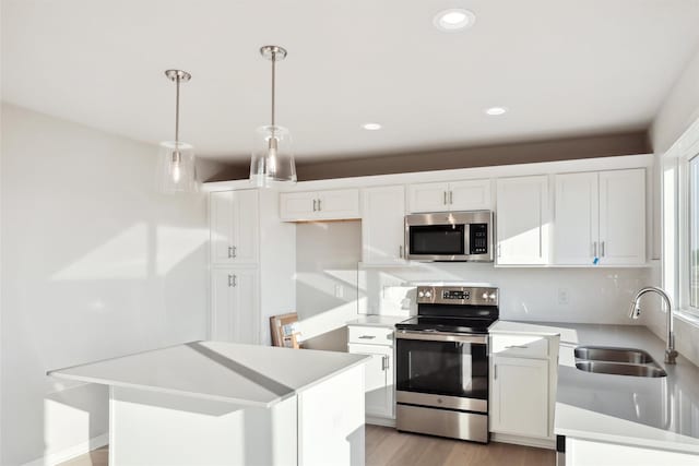 kitchen with pendant lighting, stainless steel appliances, a center island, and white cabinets