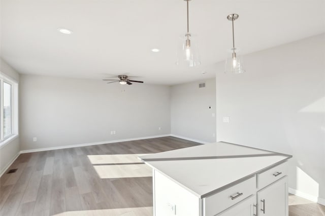 kitchen featuring a center island, light hardwood / wood-style flooring, hanging light fixtures, ceiling fan, and white cabinets