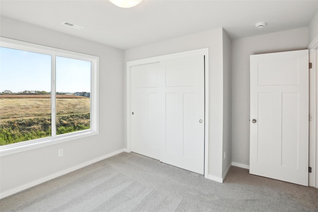 unfurnished bedroom with multiple windows, light carpet, and a closet