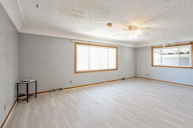 empty room with ceiling fan, a textured ceiling, and a healthy amount of sunlight