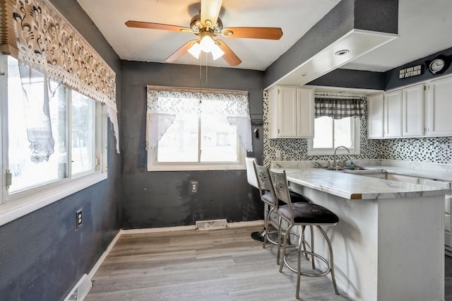 kitchen featuring plenty of natural light, white cabinets, a kitchen breakfast bar, and kitchen peninsula