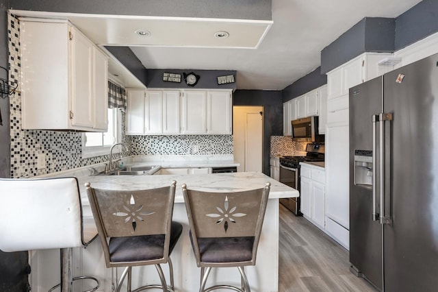 kitchen with sink, white cabinetry, light stone counters, a kitchen breakfast bar, and stainless steel appliances