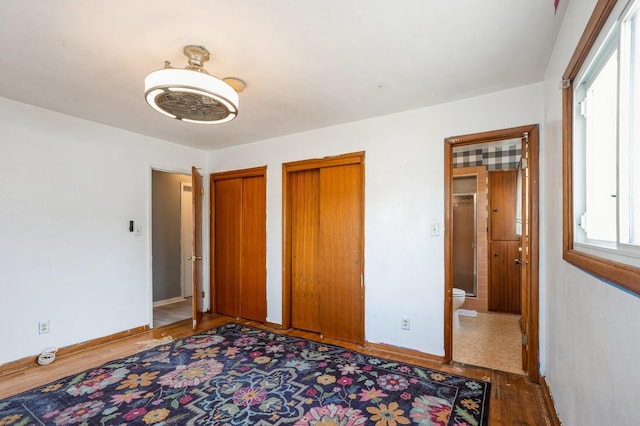 unfurnished bedroom with ceiling fan and two closets