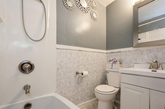 full bathroom featuring washtub / shower combination, vanity, toilet, and tile walls