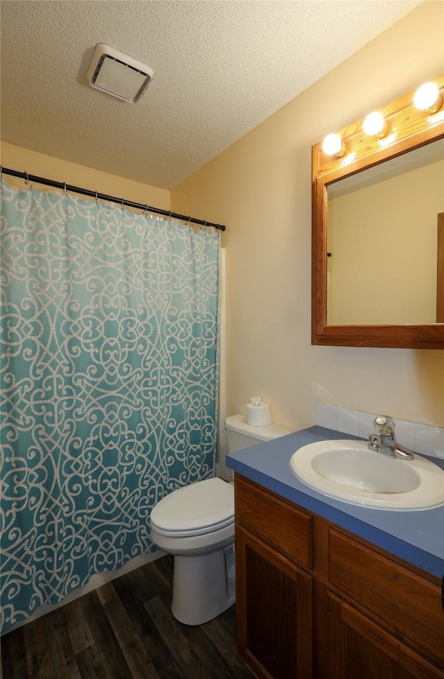 bathroom with vanity, wood-type flooring, toilet, and a textured ceiling