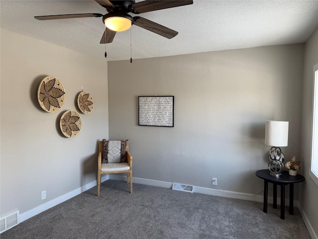 living area featuring ceiling fan, carpet, and a textured ceiling