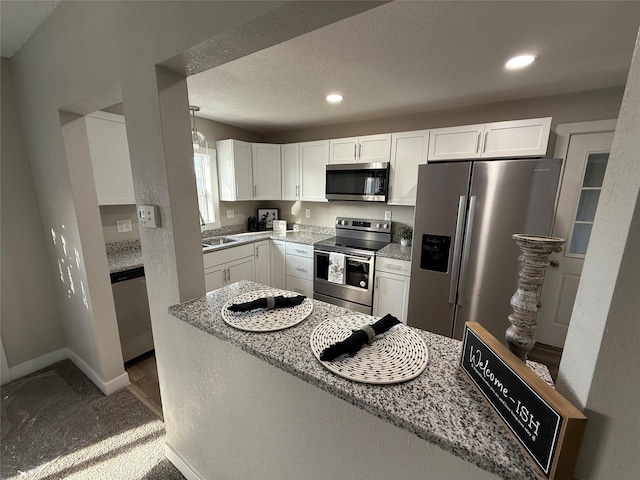 kitchen featuring light stone countertops, stainless steel appliances, white cabinets, and dark colored carpet