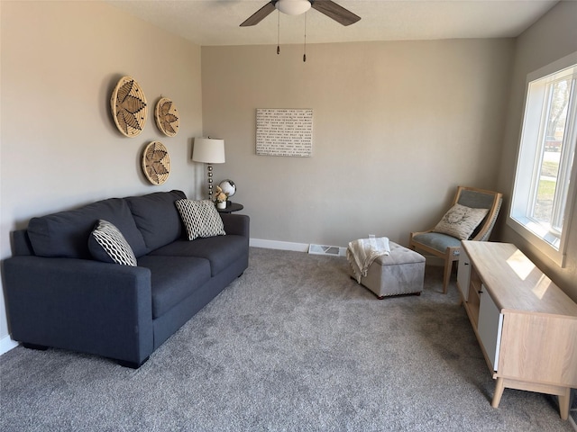 carpeted living area with baseboards, visible vents, and a ceiling fan