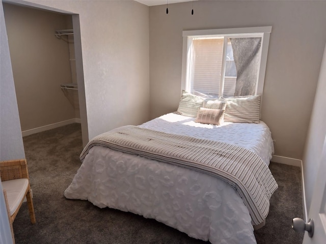 bedroom featuring carpet, a walk in closet, a closet, and baseboards