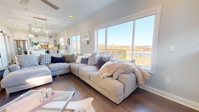 living room with dark hardwood / wood-style floors, ceiling fan, a barn door, and a wealth of natural light