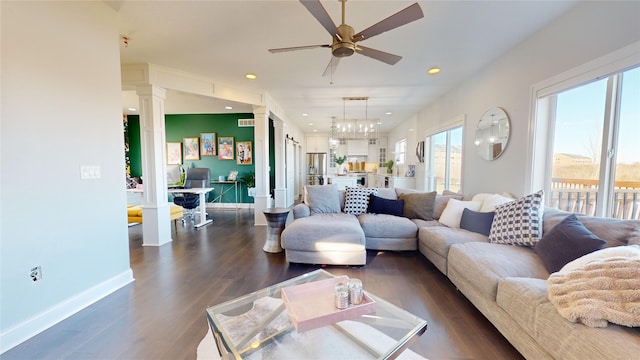 living room featuring decorative columns, dark hardwood / wood-style floors, and ceiling fan with notable chandelier