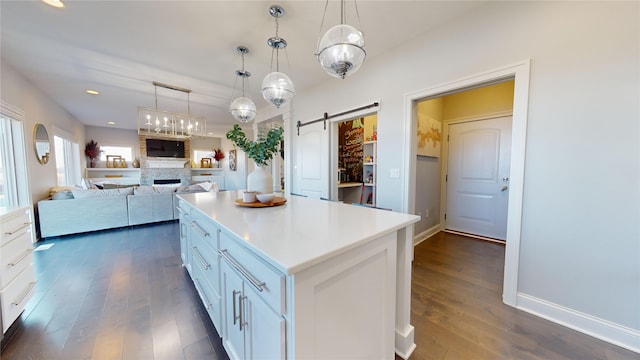 kitchen with pendant lighting, white cabinets, a center island, a barn door, and dark wood-type flooring