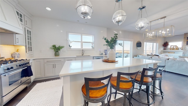 kitchen with a kitchen bar, sink, white cabinetry, custom range hood, and stainless steel appliances